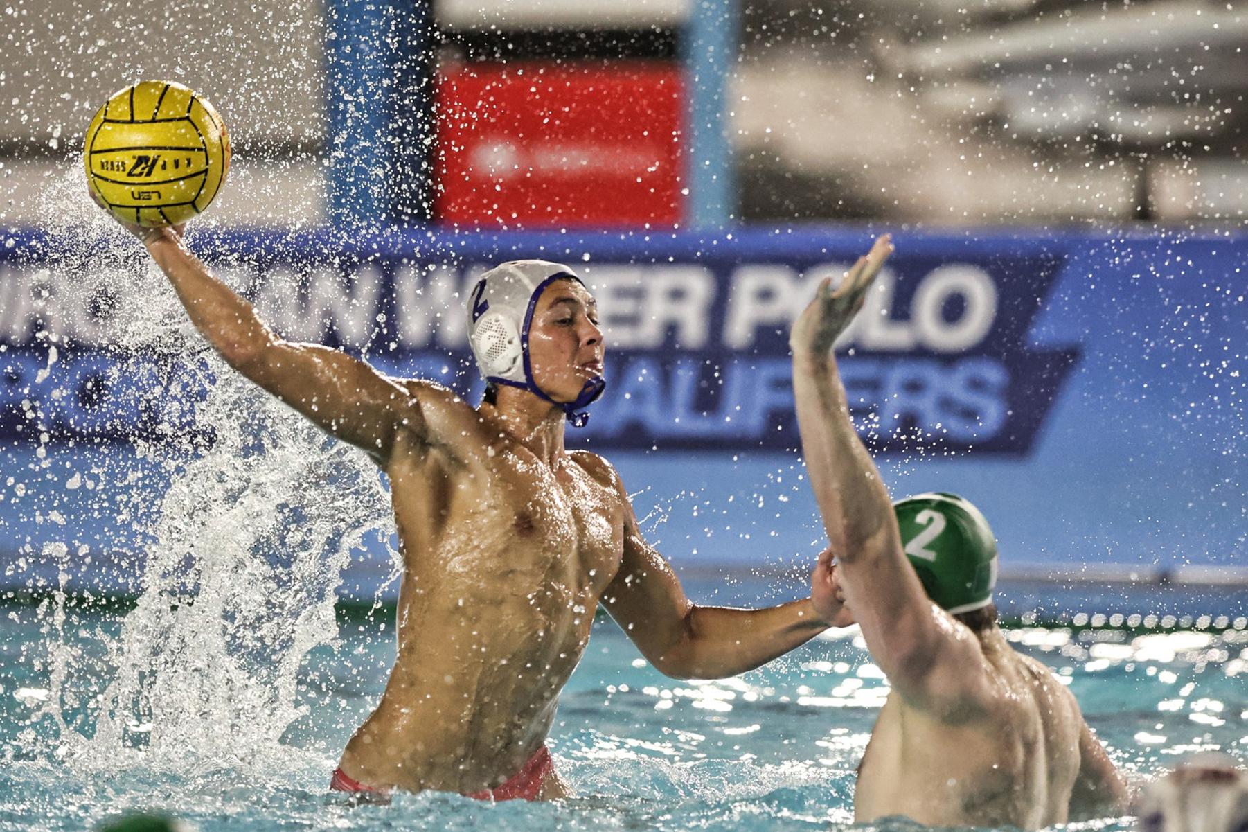Water polo player lifting the ball to shoot as a defender challenges